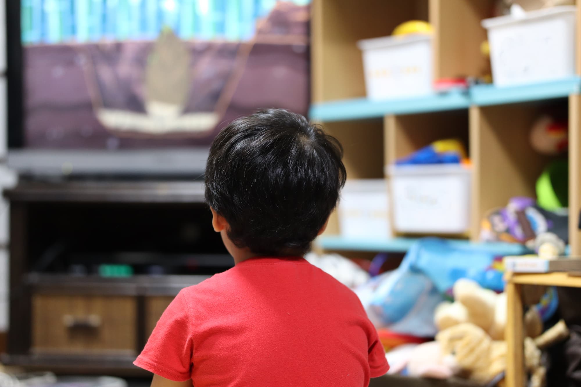 テレビを見る猫背の子どもの後ろ姿