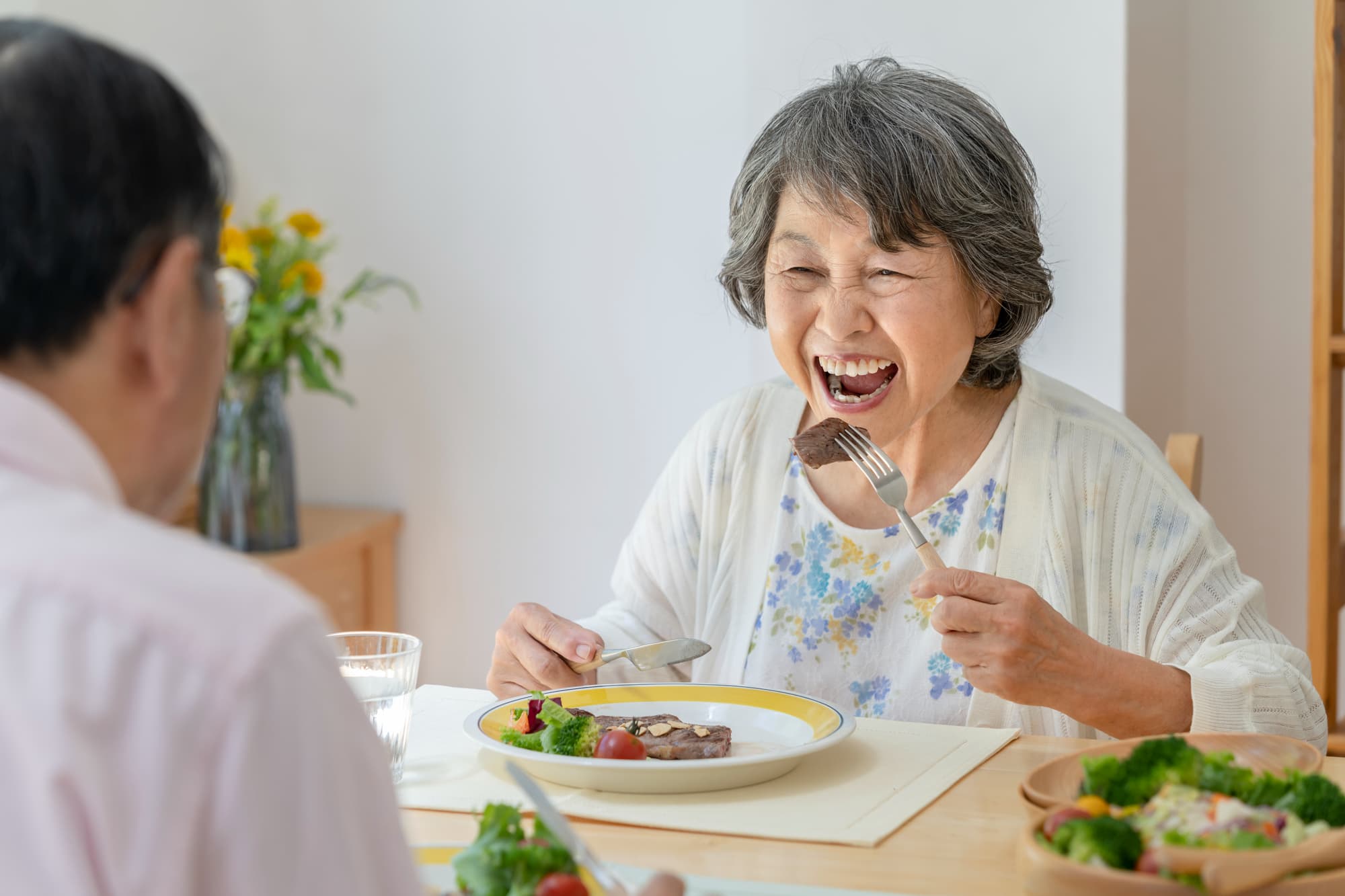 ステーキを頬張るシニア女性